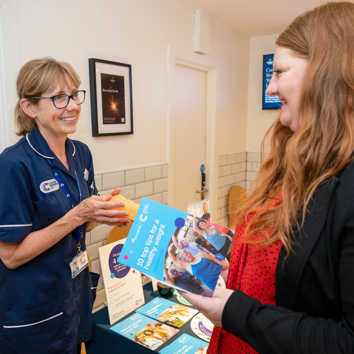 Nurse sharing information at a Cancer Research UK stand.
