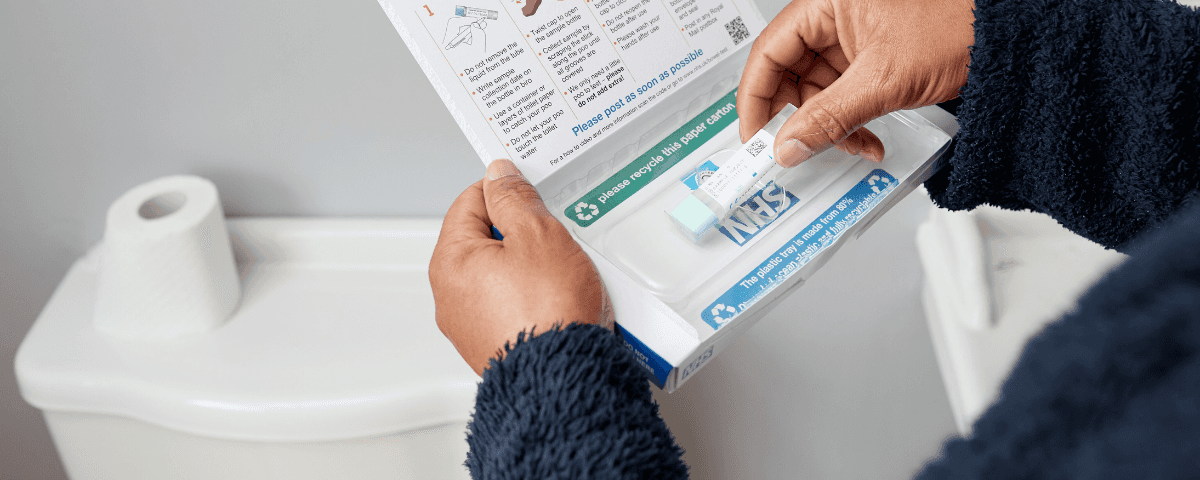 The photo shows someone in a bathroom opening a bowel cancer screening test kit from NHS England.