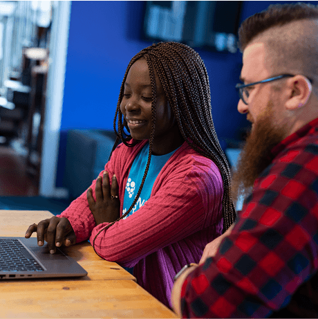 A photo of two people looking at a laptop screen.