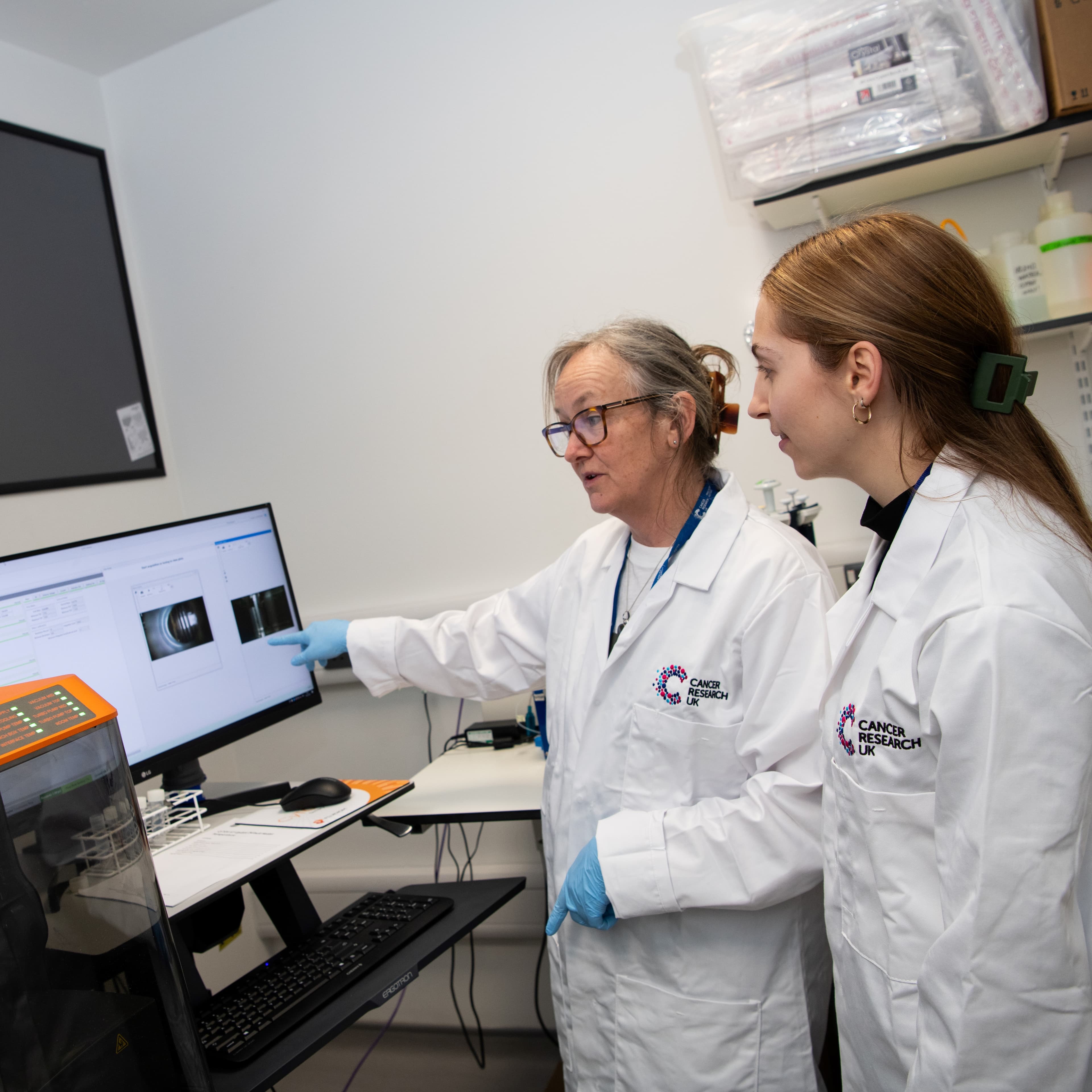 Two researchers looking at the screen and discussing.