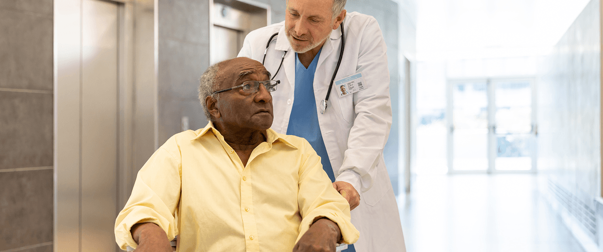 A man being pushed in a wheelchair by a doctor.