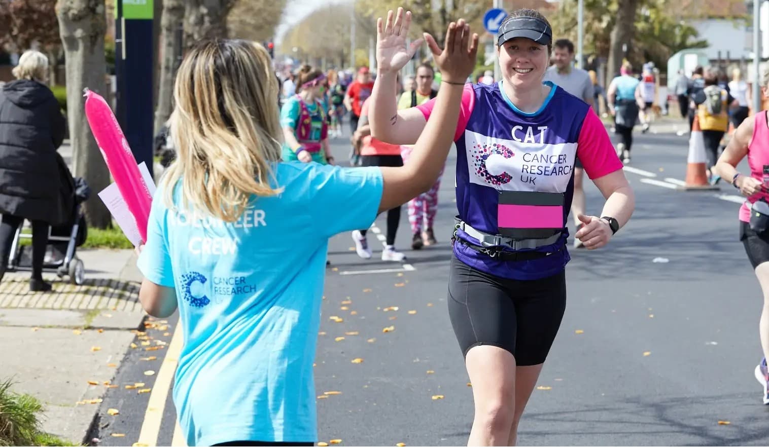Supporter running in Brighton Marathon 2022 and going in for a high five with a member of the volunteer crew.