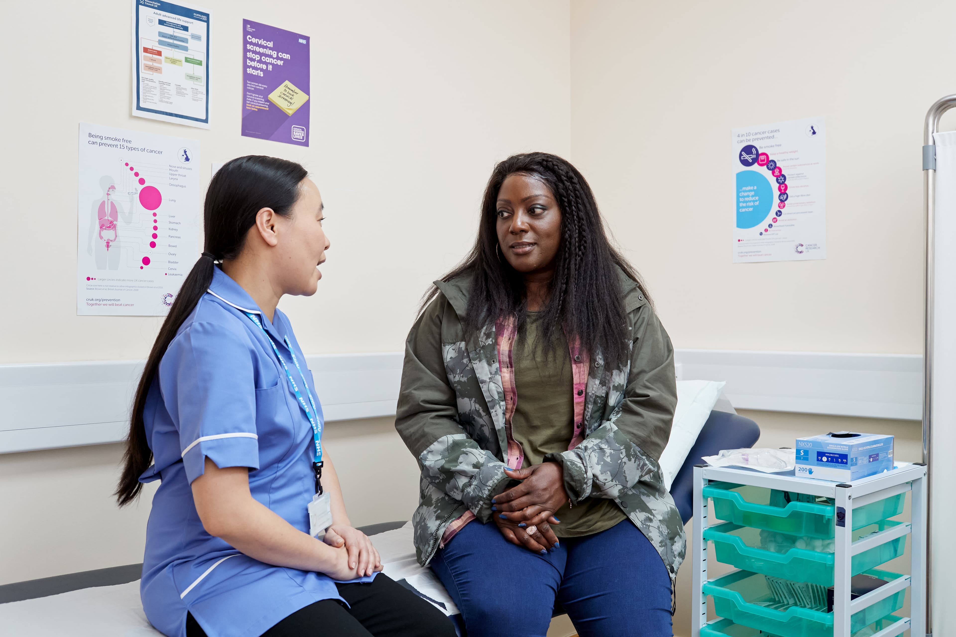 A photo of a nurse with a patient having a conversation.