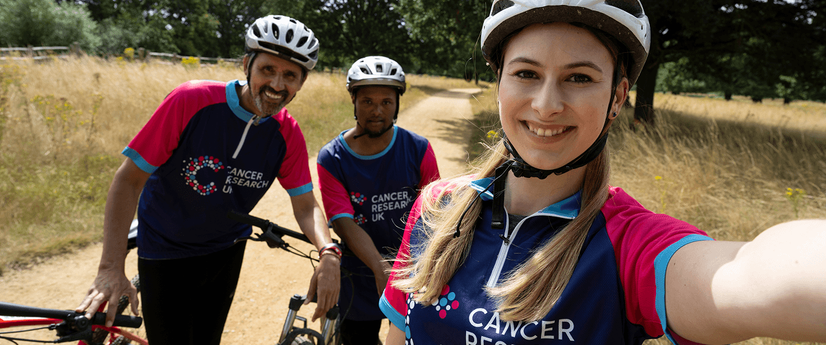 A photo of three cyclists wearing Cancer Research UK t-shirts.
