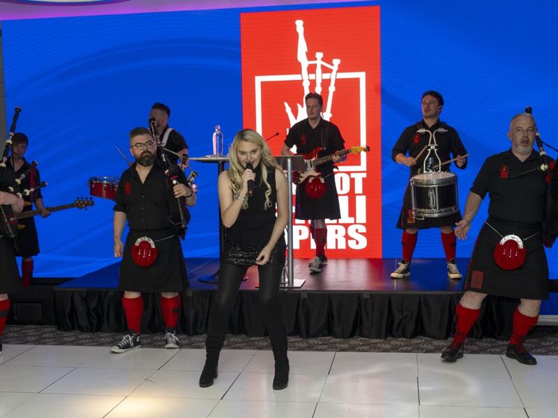 Scottish pipe band in traditional attire with singer performing