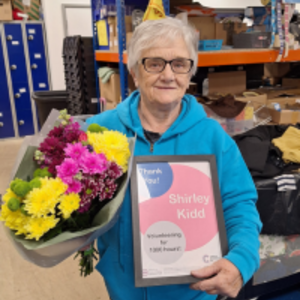 Shirley holding a bunch of flowers and a certificate