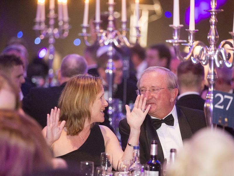 image of a man and a woman, dressed up and talking at the table of an event