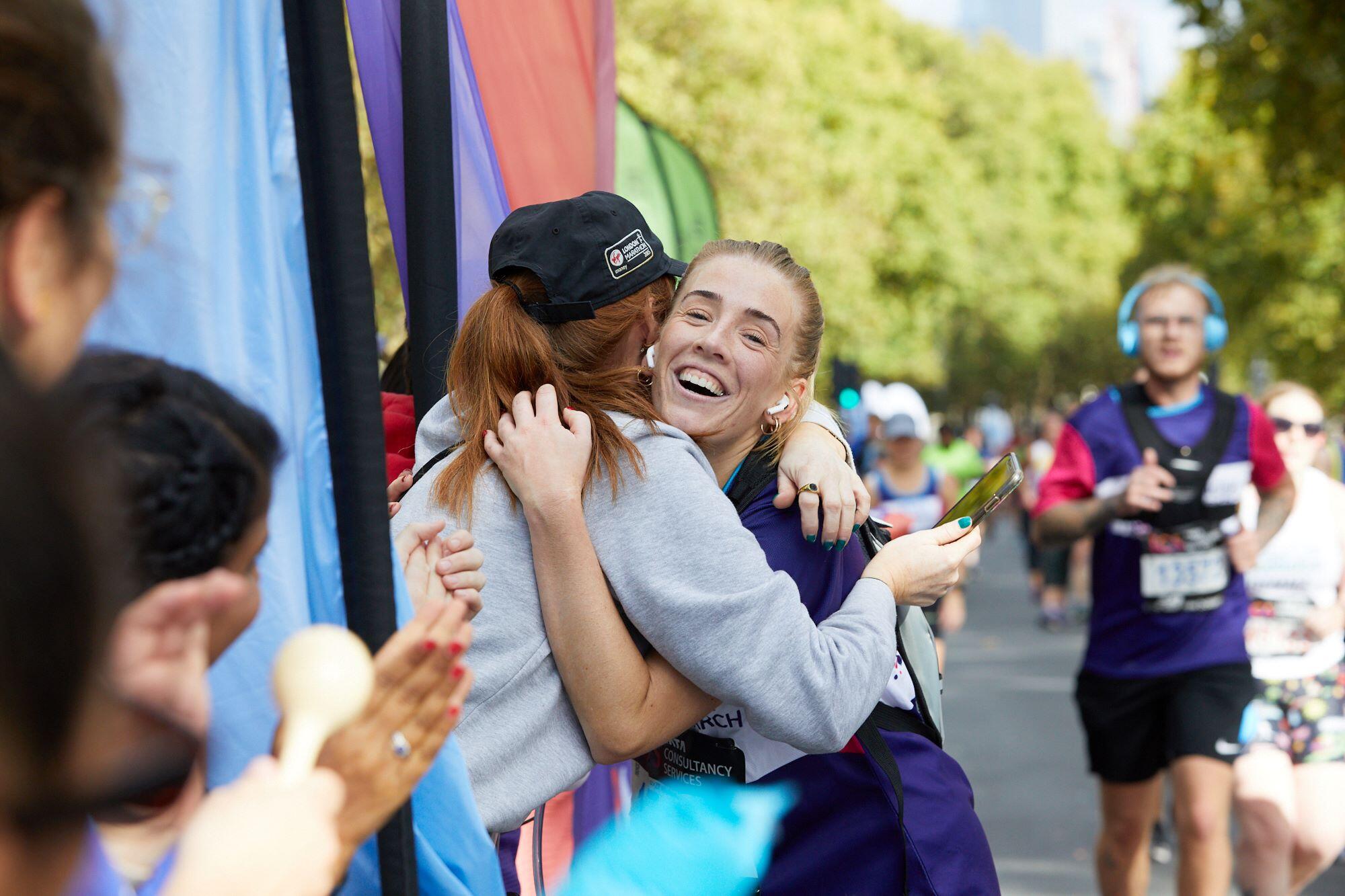 Photograph of a London Marathon runner hugging a spectator on the course
