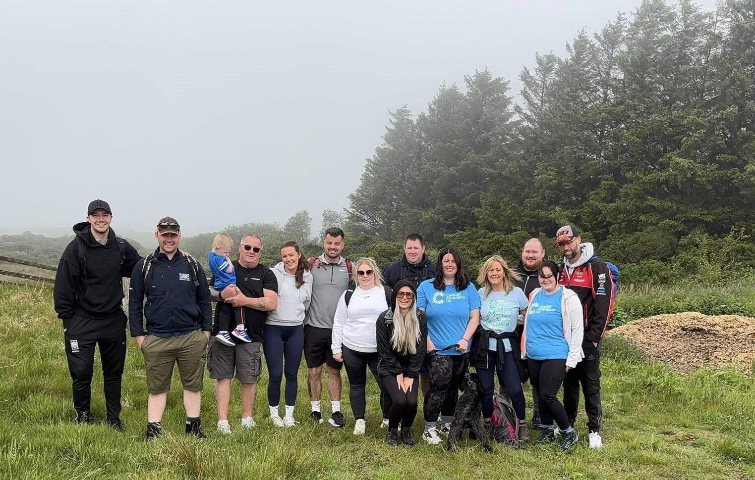 A large group of people standing outside in the woodlands. Some are wearing Cancer Research UK t-shirts.