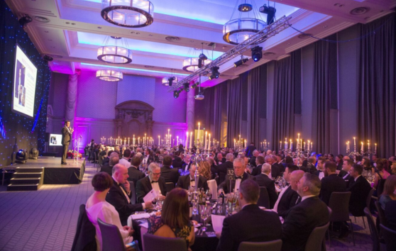 A large group of people sitting round tables at a formal event