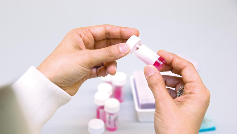 Researcher's hands holding a tube of liquid