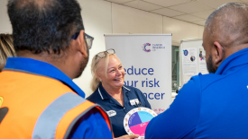 Two employees and a Cancer Research UK nurse discuss cancer awareness.