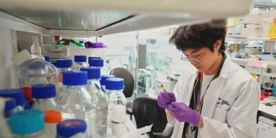 Researcher in a lab, in the forefront of the image are a number of bottles and containers.