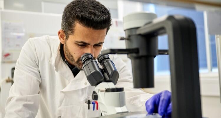 A scientist looking down a microscope.