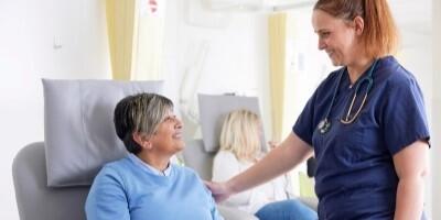 Two people in a treatment room, one appears to be a patient and the other a healthcare practitioner. They are smiling at each other.