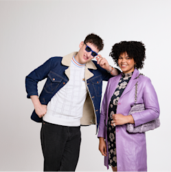 2 people standing and smiling, one person is leaning on the other ones shoulder