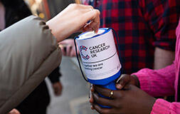 A photo of a person donating money into a goblet