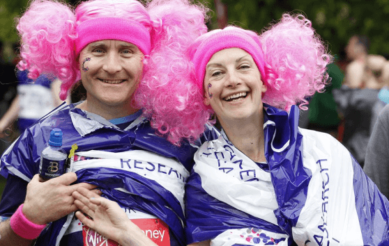Get fundraising support A man and a woman in pink wigs smiling fundraising for CRUK