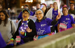 Shine night walk participants, wearing lights and wings, looking happy