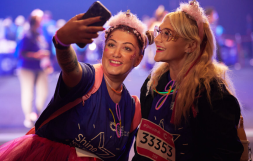 Two Shine Night Walk participants wearing pink fluffy headbands and face glitter, taking a selfie