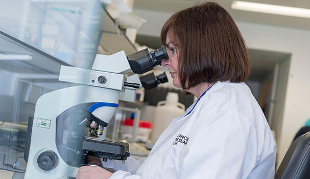Researcher looking down microscope