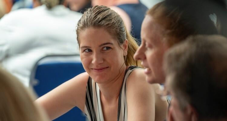 Smiling woman looking at someone sitting next to her.