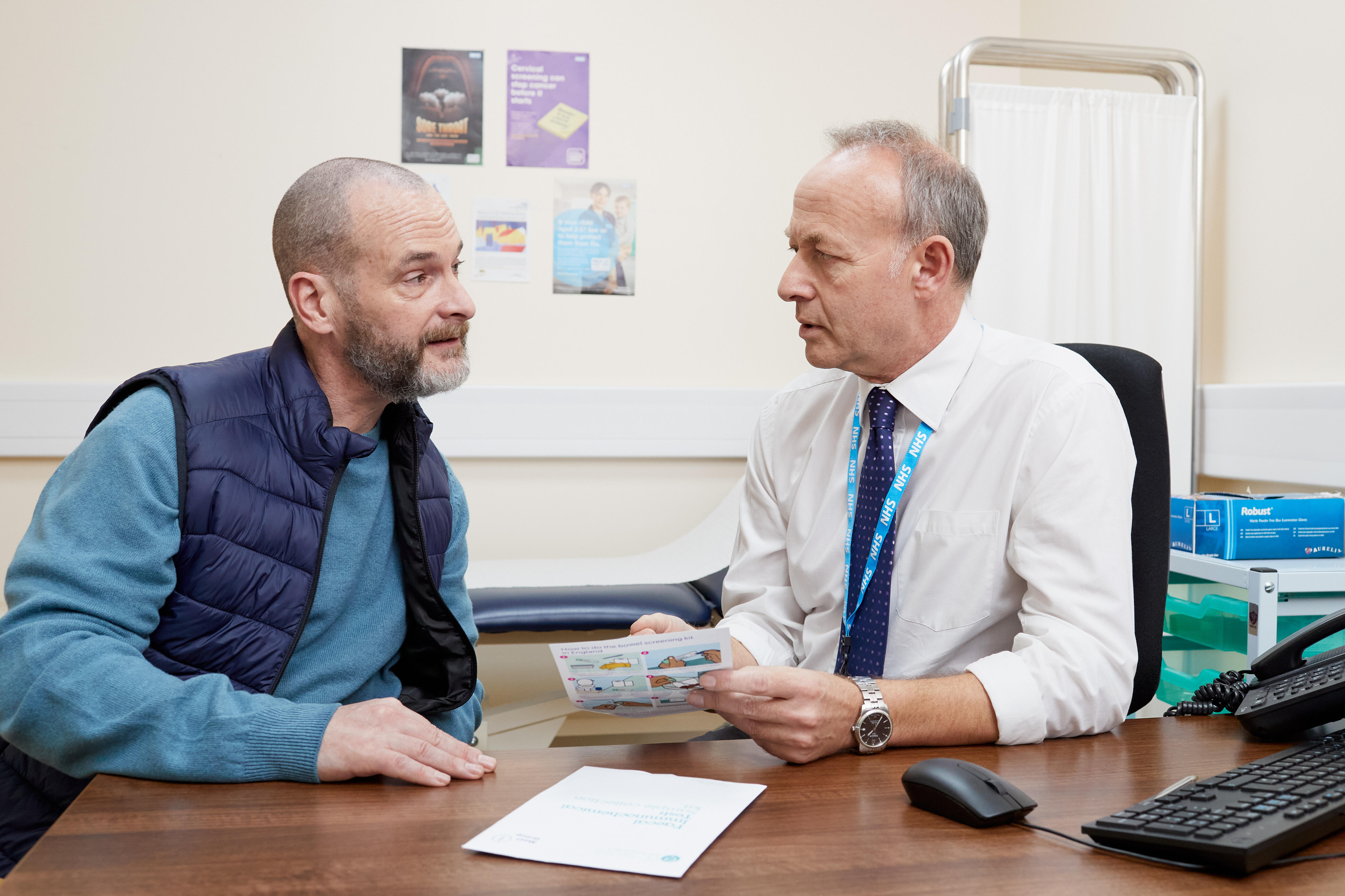 A photo of a man talking to a doctor