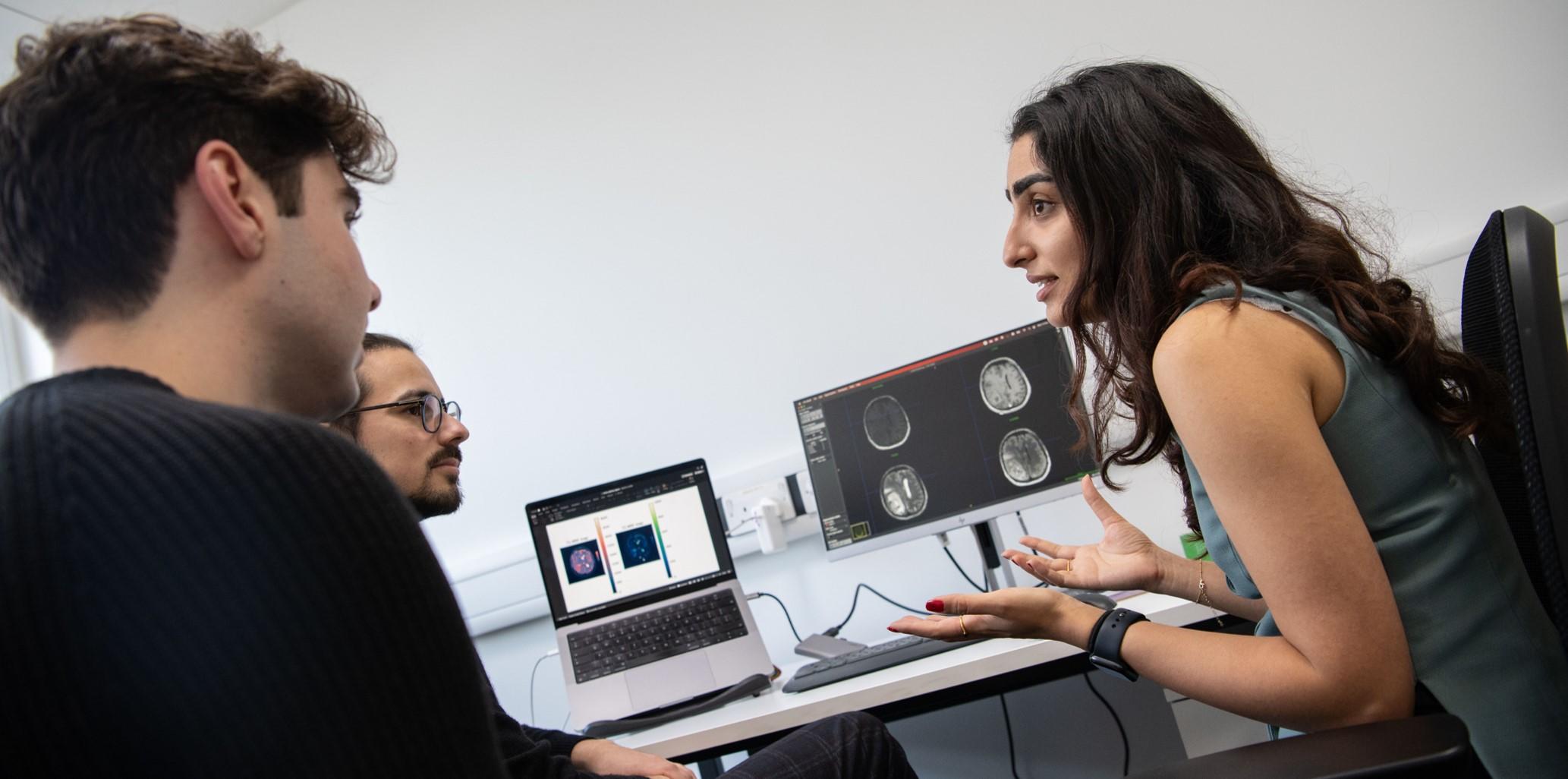 Researchres at a desk looking at data on the screen