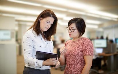 Two women standing in discussion looking at documents