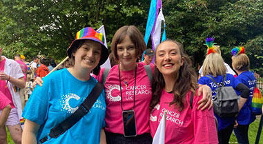 A photo of people wearing CRUK t-shirts and smiling at a Pride parade