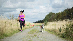 A person running outdoors with a dog