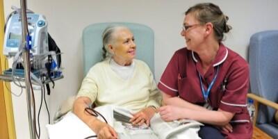 Two people in a treatment room, one appears to be a patient and the other a healthcare practitioner. They are smiling at each other.