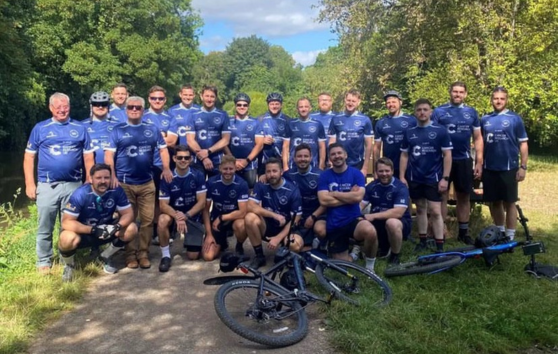 A group of men smiling for a photo in cycling gear, with bikes in front of them