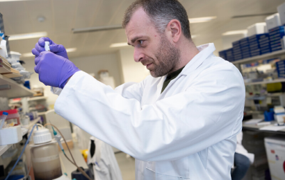 Image of male researcher in white lab coat working in a lab