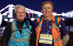 Image of two male Shine Night Walk volunteers in reflective vests, smiling