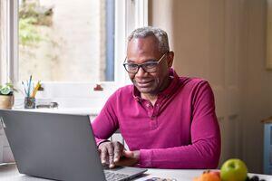 a man sat at a table looking at his laptopn
