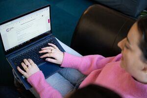 A women typing on their laptop and the laptop screen shows a Cancer Research UK form