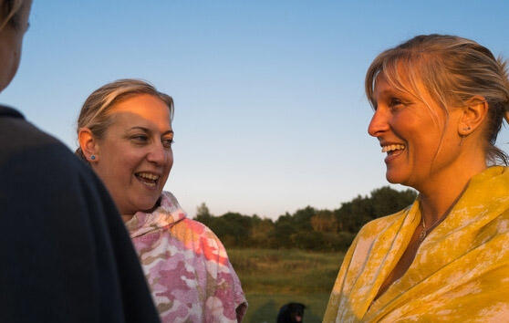 Photo of three smiling women chatting in the evening sun