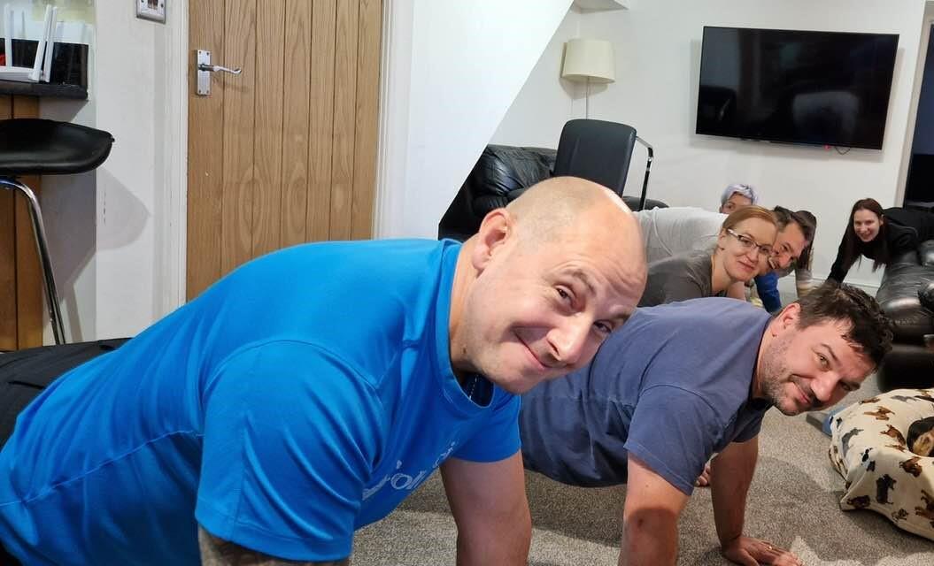 Picture of a group of people smiling doing push-ups