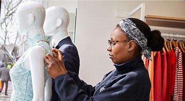 Portrait of a volunteer dressing a mannequin in a charity shop